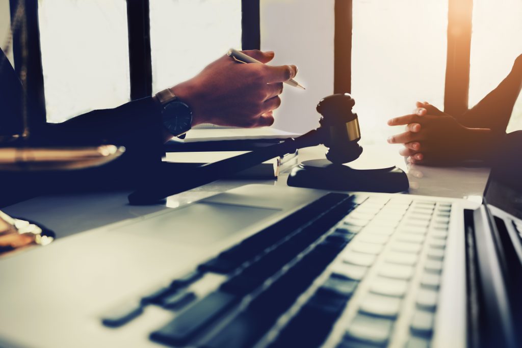 law and justice concept, client discussion lawyer judgement lawsuit with holding pen, law book,gavel and scales of justice at table in office.